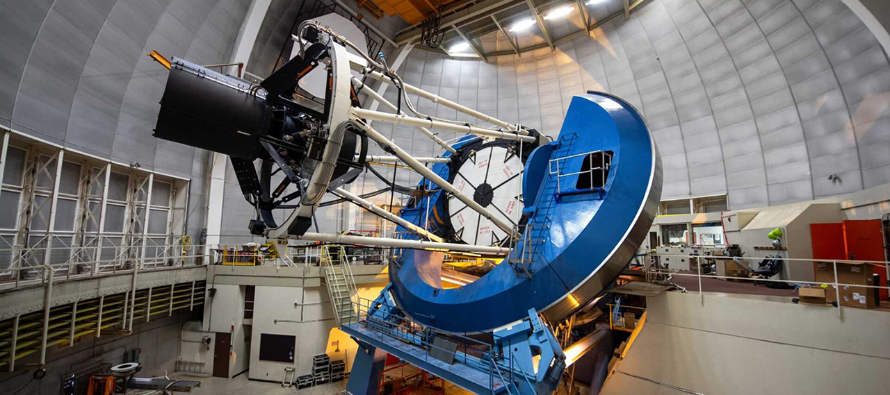 Side view of the Dark Energy Spectroscopic Instrument, used to detect dark energy and map the expanding universe, atop a large telescope.